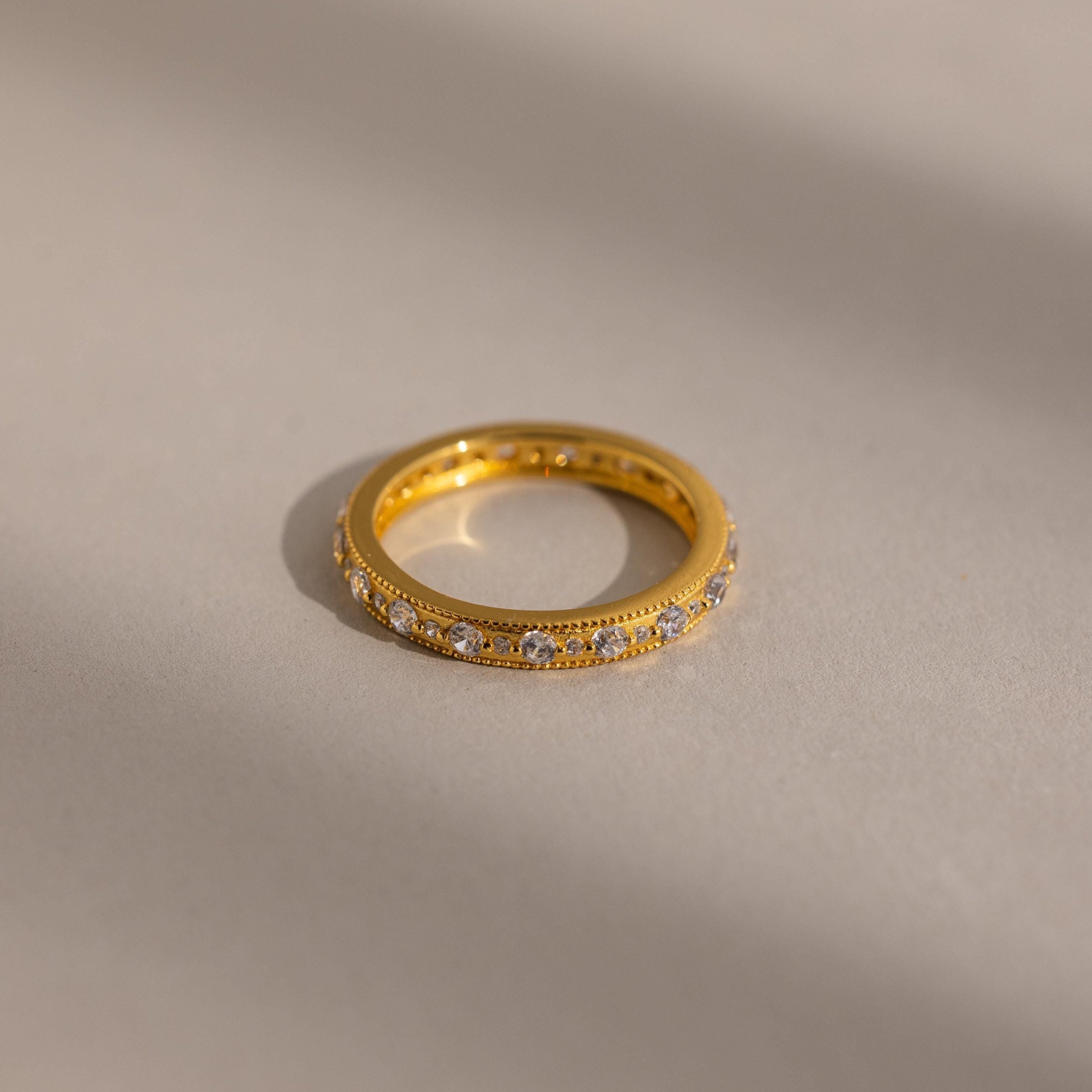 Gold ring with embedded stones on a beige background
